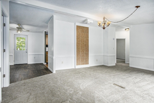 carpeted empty room featuring a textured ceiling, beamed ceiling, and ceiling fan with notable chandelier