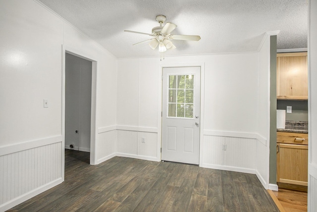 unfurnished dining area featuring dark hardwood / wood-style floors, ceiling fan, ornamental molding, and a textured ceiling