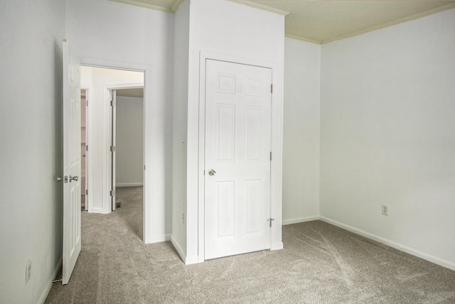 unfurnished bedroom featuring light colored carpet, a closet, and crown molding