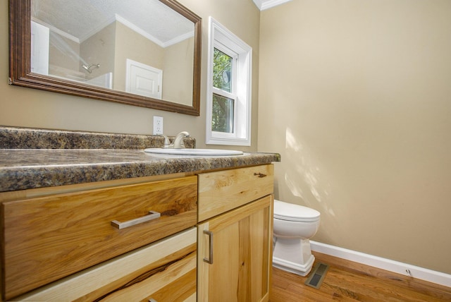 bathroom featuring crown molding, vanity, wood-type flooring, and toilet