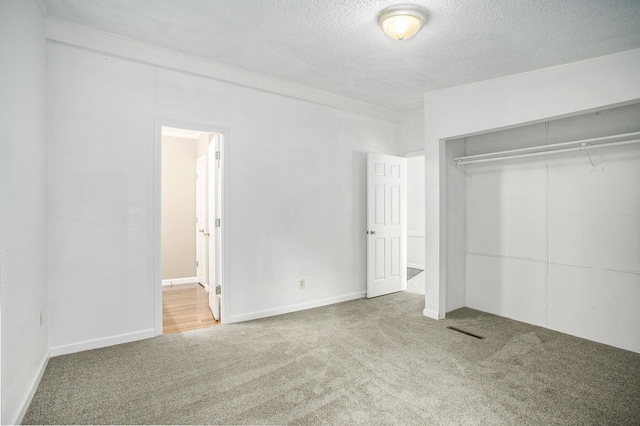 unfurnished bedroom featuring a closet, carpet, a textured ceiling, and ornamental molding