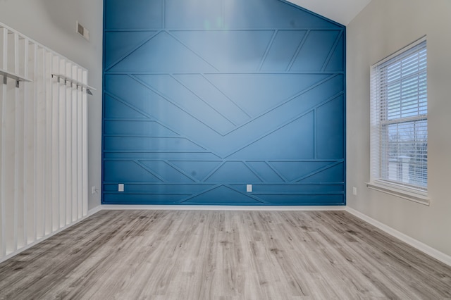 unfurnished room featuring light hardwood / wood-style floors and lofted ceiling