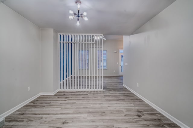 empty room featuring a chandelier and light hardwood / wood-style flooring