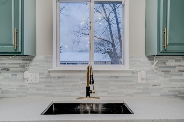 interior details featuring decorative backsplash, light stone countertops, sink, and green cabinetry