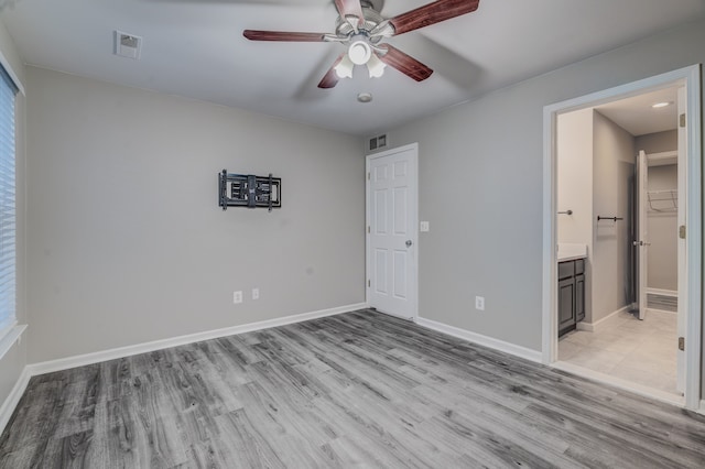 unfurnished bedroom with light wood-type flooring, ensuite bath, and ceiling fan