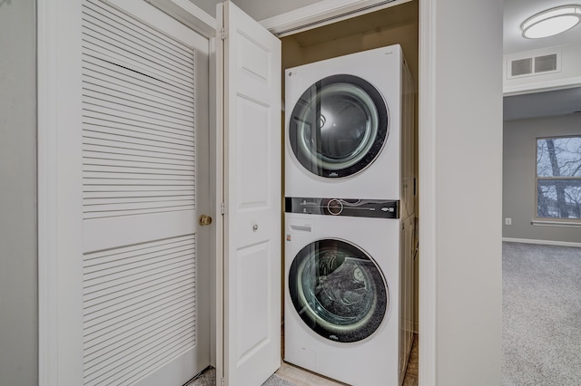 laundry area featuring light carpet and stacked washer and dryer