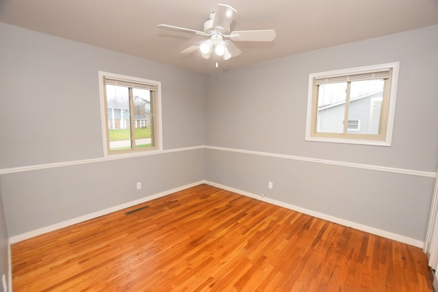 empty room featuring a wealth of natural light, ceiling fan, and hardwood / wood-style flooring