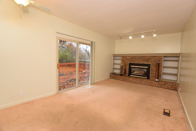 unfurnished living room featuring ceiling fan, carpet floors, a fireplace, and track lighting