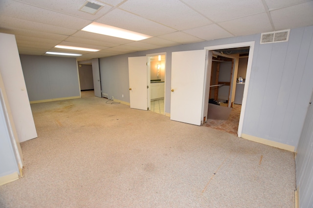 basement with a drop ceiling and light colored carpet