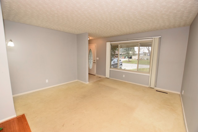 carpeted empty room featuring a textured ceiling