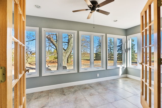 unfurnished sunroom featuring ceiling fan