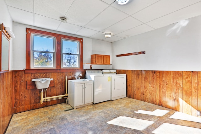 laundry room featuring washer and dryer, wood walls, and cabinets