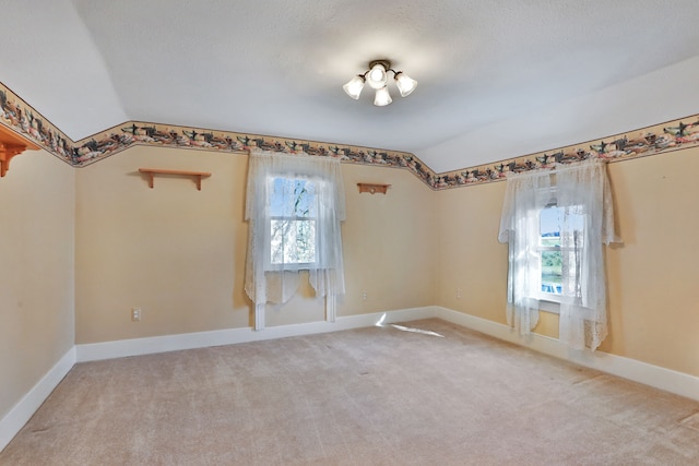 unfurnished room with carpet, a textured ceiling, a wealth of natural light, and lofted ceiling