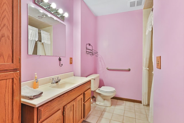 bathroom with toilet, vanity, and tile patterned floors