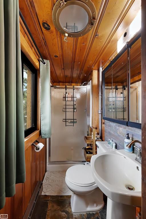 bathroom featuring wood walls, a shower with door, wooden ceiling, sink, and decorative backsplash