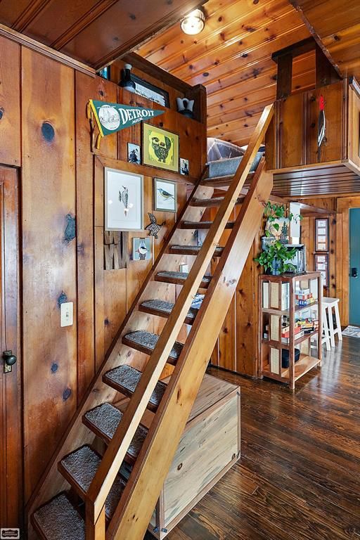 staircase featuring wood walls, wooden ceiling, and hardwood / wood-style flooring