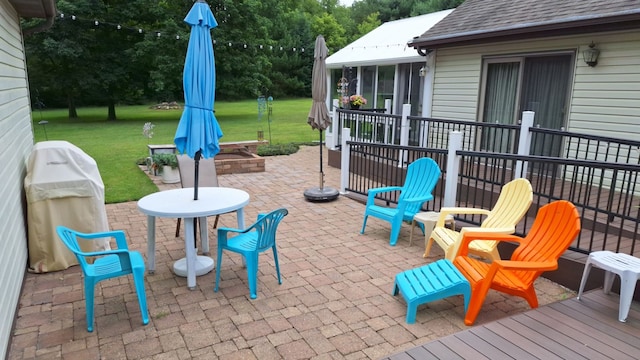 view of patio / terrace featuring area for grilling, an outdoor fire pit, and a sunroom