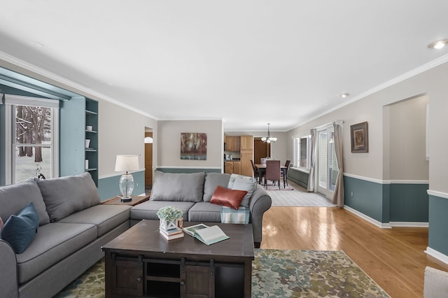 living room featuring crown molding, a chandelier, and light wood-type flooring