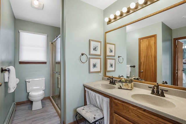 bathroom with toilet, vanity, hardwood / wood-style floors, baseboard heating, and a shower with door