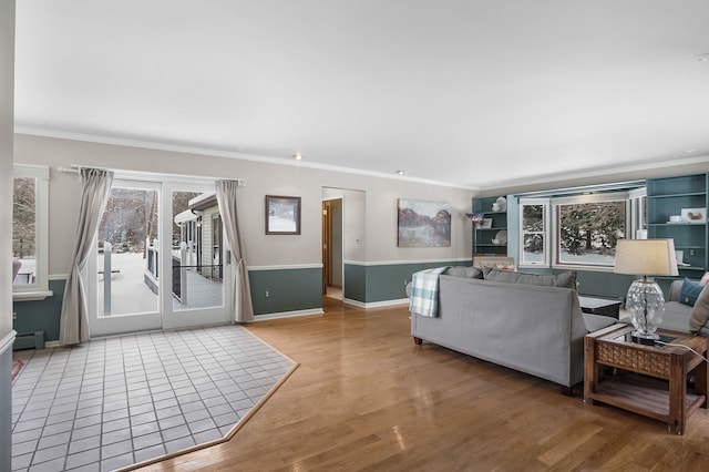 living room with a baseboard heating unit, ornamental molding, and hardwood / wood-style floors