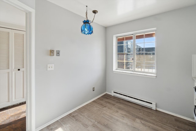 unfurnished dining area featuring hardwood / wood-style floors and a baseboard radiator