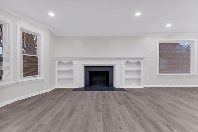 unfurnished living room with built in shelves and light hardwood / wood-style floors