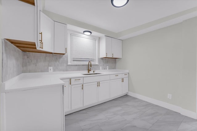 kitchen with backsplash, white cabinetry, and sink