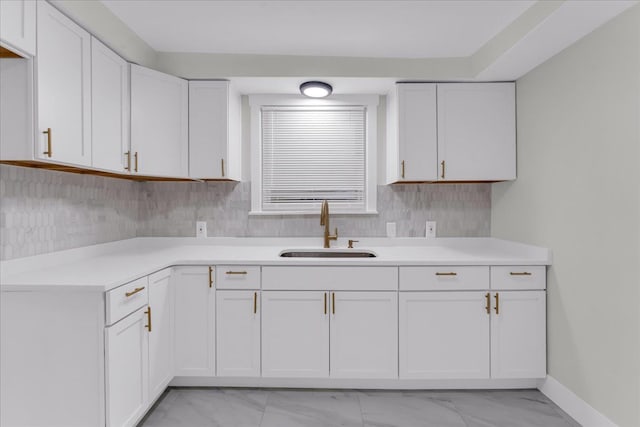 kitchen with decorative backsplash, white cabinetry, and sink