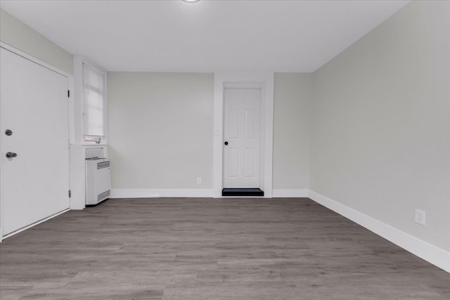 unfurnished room with radiator and wood-type flooring