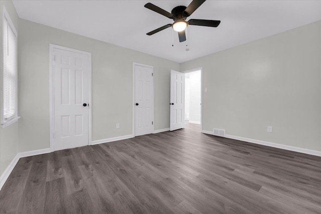 unfurnished bedroom featuring two closets, ceiling fan, and dark hardwood / wood-style floors