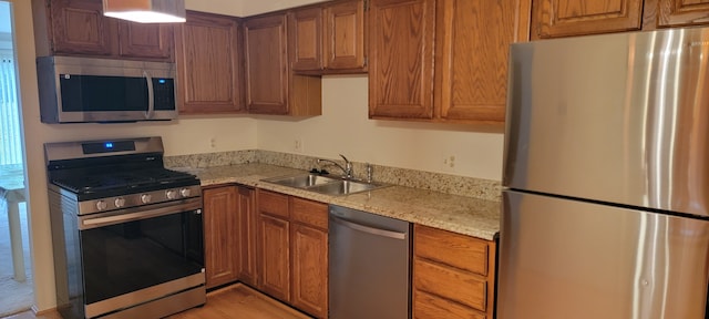 kitchen with stainless steel appliances, sink, and light stone counters