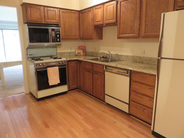 kitchen with light stone countertops, sink, white appliances, and light hardwood / wood-style floors