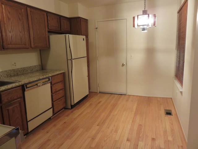 kitchen with decorative light fixtures, a chandelier, light hardwood / wood-style floors, light stone counters, and white appliances