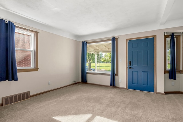 carpeted foyer entrance with beam ceiling