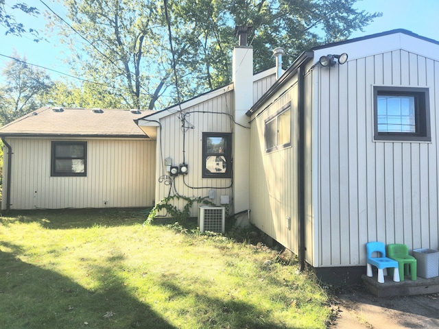 view of home's exterior with cooling unit and a lawn