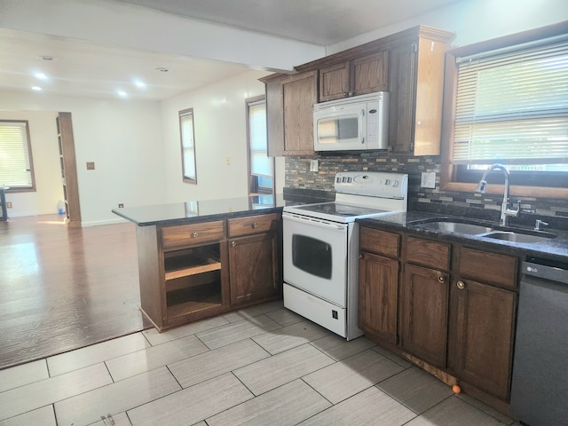 kitchen featuring sink, tasteful backsplash, kitchen peninsula, white appliances, and dark brown cabinets