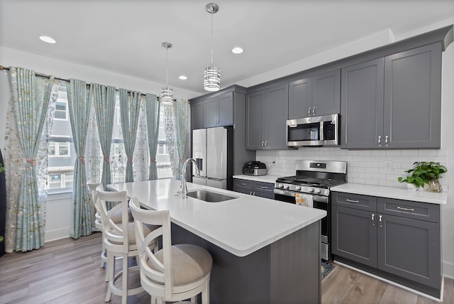 kitchen with pendant lighting, gray cabinetry, sink, and stainless steel appliances