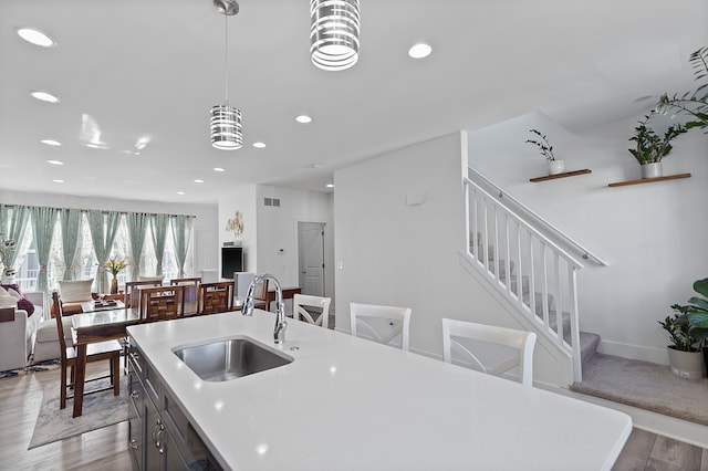 kitchen with decorative light fixtures, light hardwood / wood-style floors, a notable chandelier, and sink