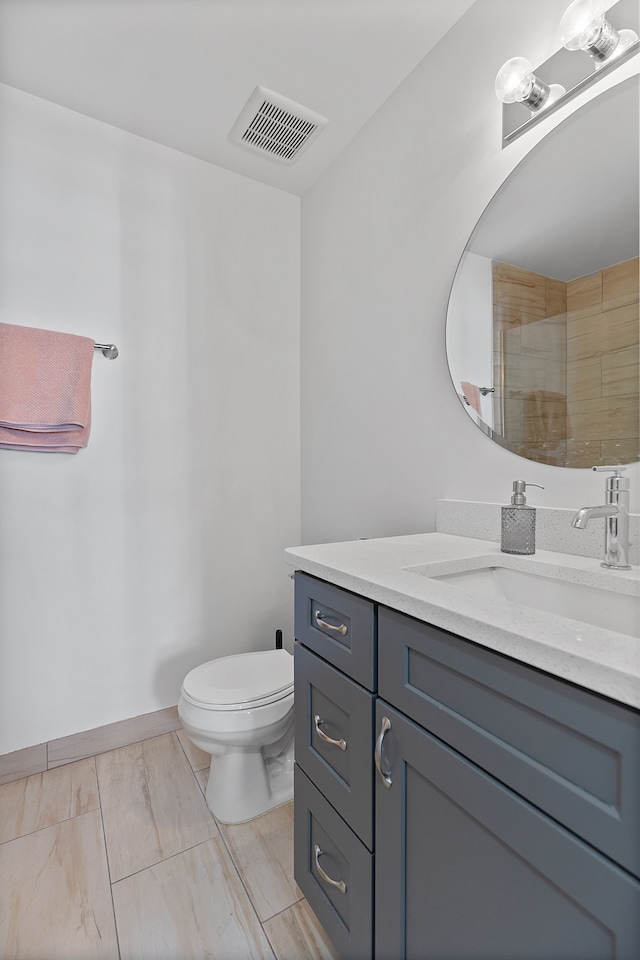 bathroom featuring vanity, a shower with shower door, and toilet