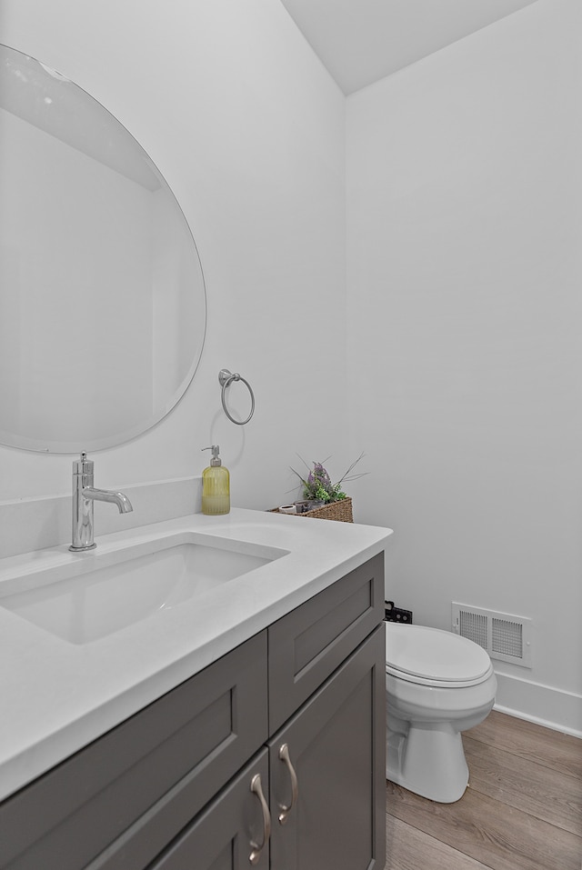 bathroom with hardwood / wood-style flooring, vanity, and toilet