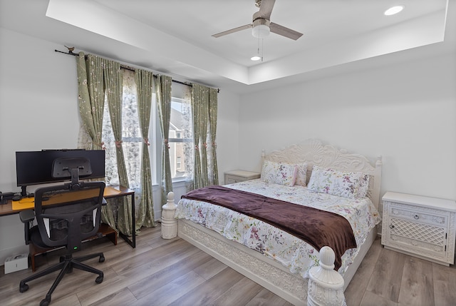 bedroom with a tray ceiling, ceiling fan, and light hardwood / wood-style floors