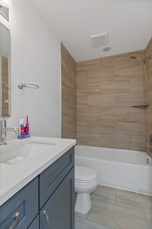 full bathroom with tiled shower / bath, tile patterned flooring, vanity, and toilet