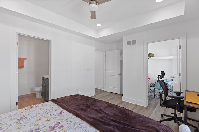 bedroom featuring a tray ceiling, ceiling fan, and light wood-type flooring