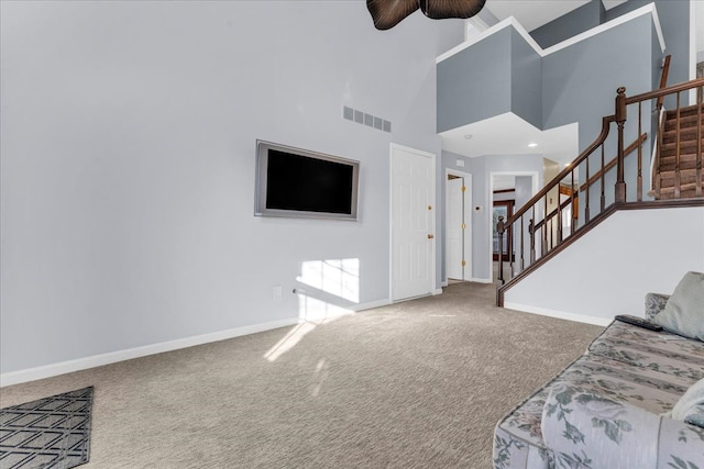 carpeted living room with a high ceiling and ceiling fan