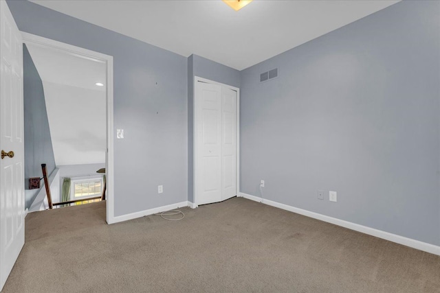 unfurnished bedroom with carpet flooring, a closet, and lofted ceiling