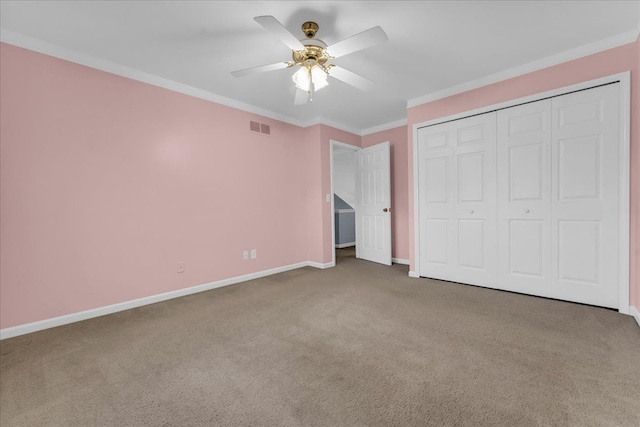 unfurnished bedroom with ceiling fan, a closet, carpet, and ornamental molding