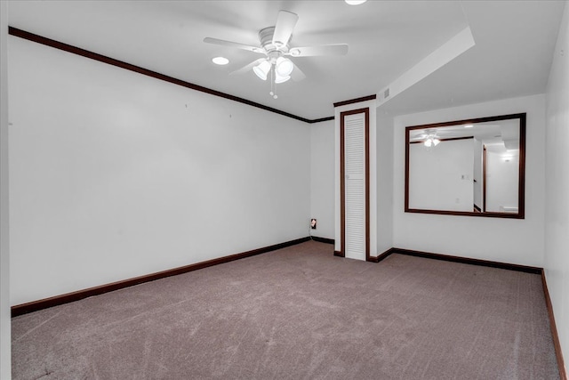 carpeted spare room featuring ceiling fan and crown molding