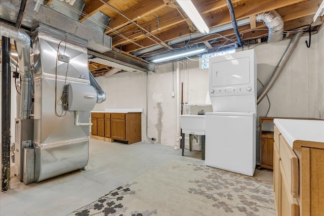 basement featuring heating unit, stacked washer and dryer, and sink