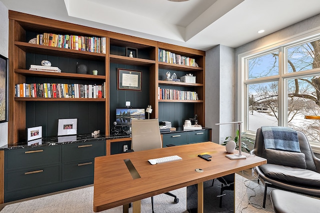 home office with built in features and a raised ceiling