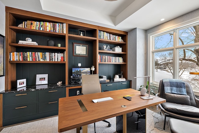 office space with built in shelves and a raised ceiling